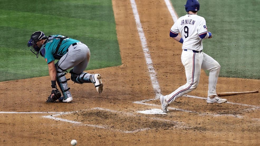Danny Jansen #9 of the Texas Rangers scores in front of Mitch Garver #18 of the Seattle Mariners during the fifth inning at Globe Life Field on April 08, 2026 in Arlington, Texas. (Photo by Stacy Revere/Getty Images)