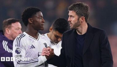 Manchester United head coach Michael Carrick (right) shakes hands with Kobbie Mainoo