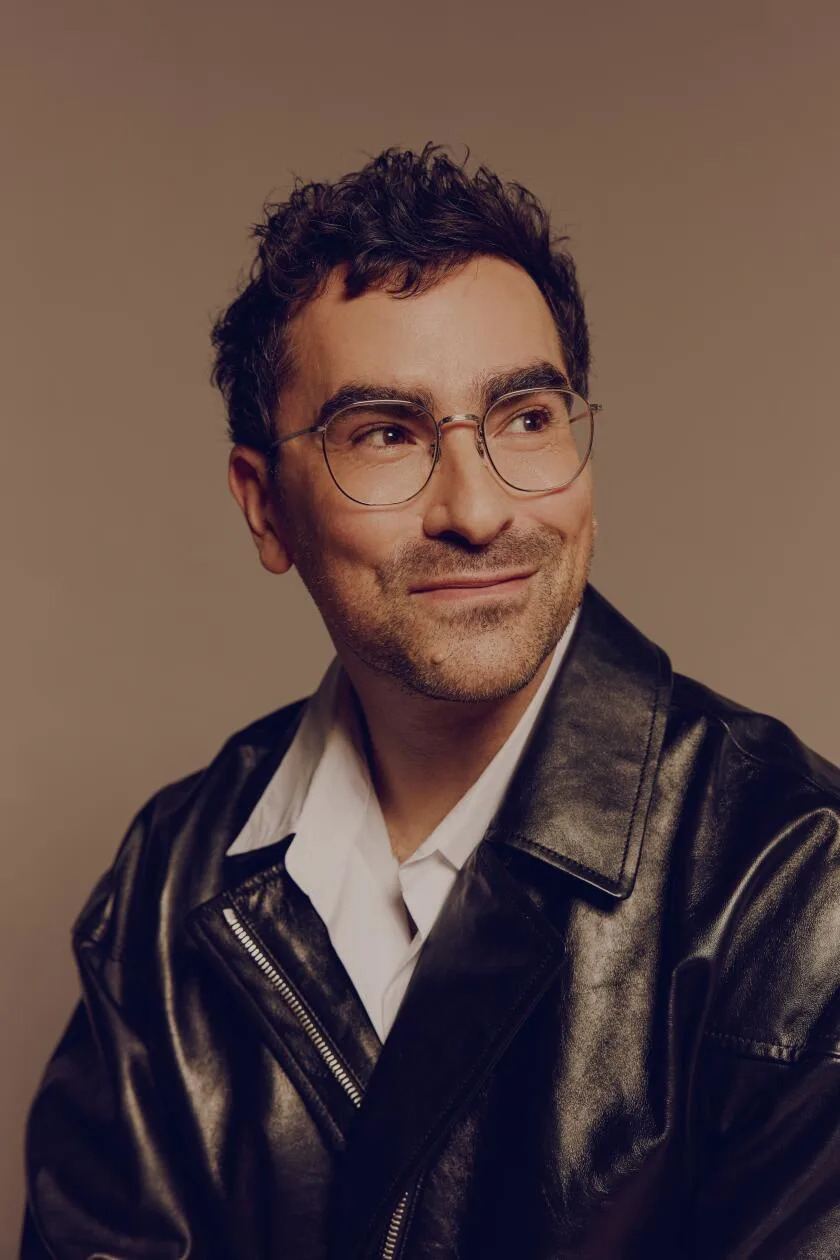 A smiling man in glasses looks to the side.