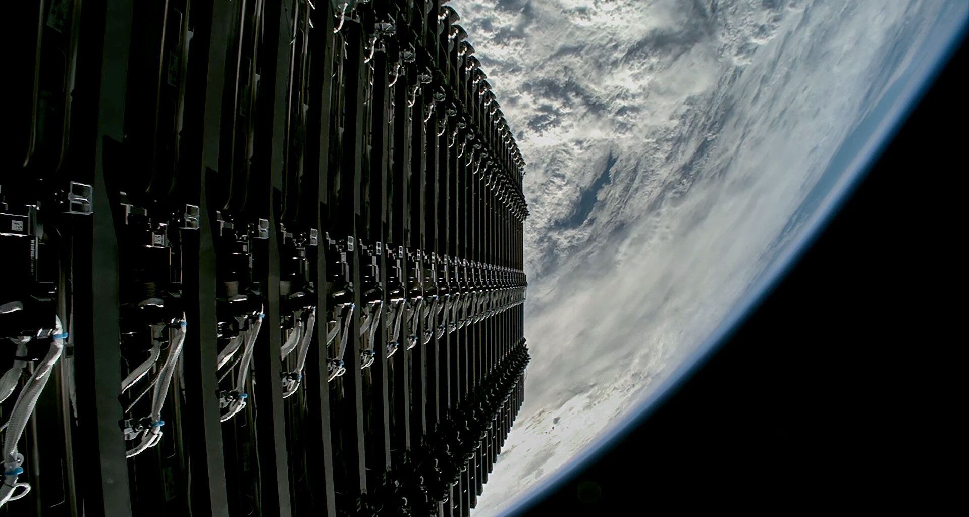 A stacked group of satellites is seen just before their deploy into orbit above a blue and white Earth.