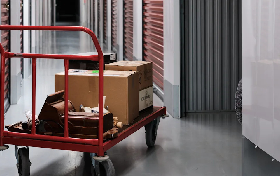 Boxes on a red metal cart in a storage facility hallway, depicting organized storage or moving materials