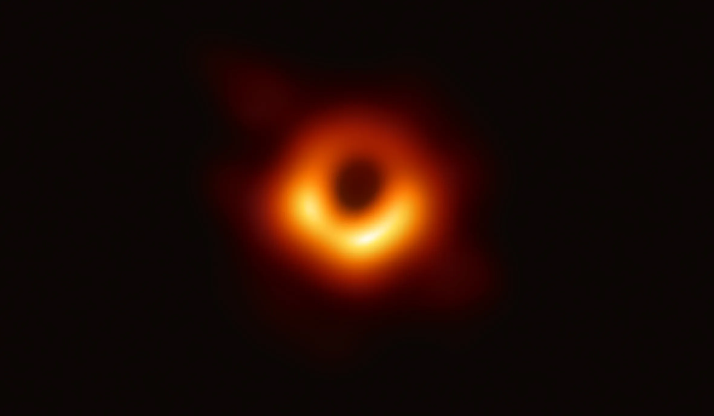 First image of a black hole with a fiery orange and yellow halo, set against a dark background.