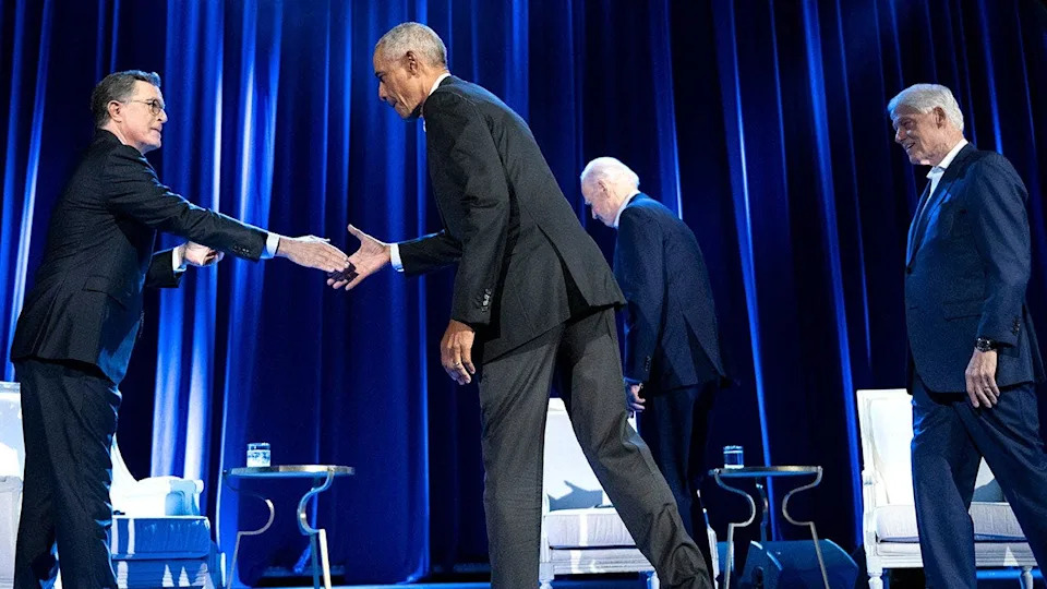 Biden, Clinton walk to their seats as Obama greets Stephen Colbert at fundraising event.
