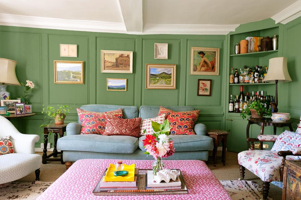 Living room with green walls, decorative art, and floral arrangements.