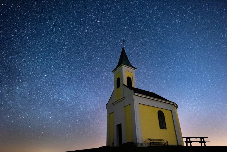 Shooting stars in a night sky above a church.