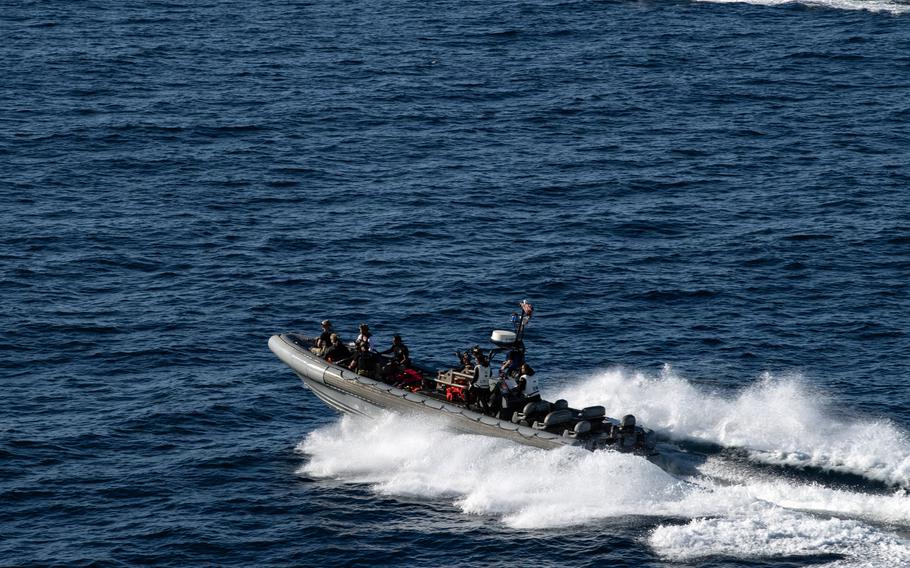 Navy divers drive an inflatable boat in the water.