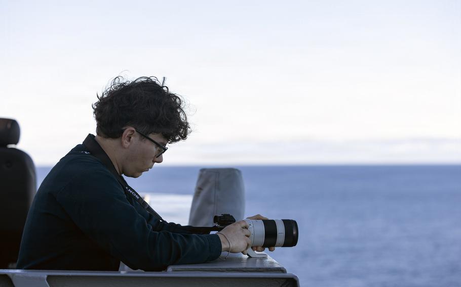A sailor holds a camera to take photos at sea.