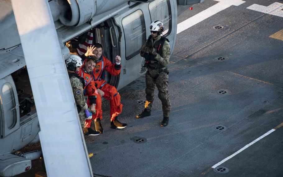 Reid Wiseman and Jeremy Hansen look up from a helicopter and smile.