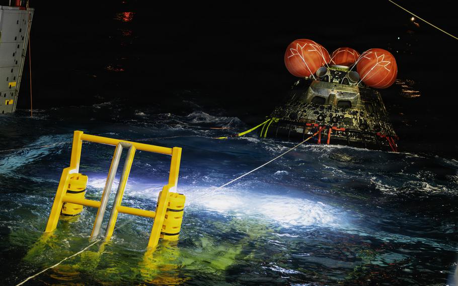 The Orion spacecraft is pulled by a rope from the water.