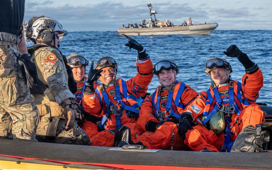 Four NASA astronauts sit in a boat together and smile.