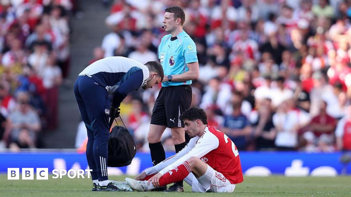 Kai Havertz sits on the pitch while a physio stands over him after injuring himself against Newcastle
