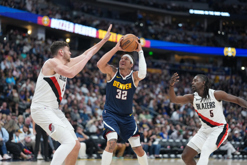 Denver Nuggets forward Aaron Gordon, center, drives to the basket between Portland Trail Blazers center Donovan Clingan, left, and guard Jrue Holiday in the second half of an NBA basketball game Monday, April 6, 2026, in Denver. (AP Photo/David Zalubowski)