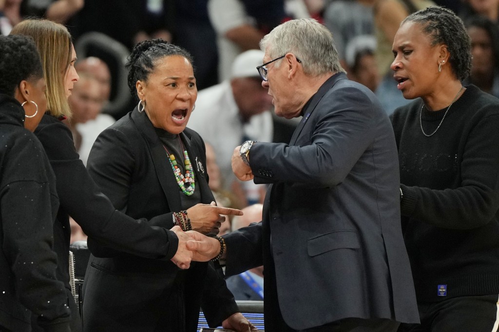 Coaches Dawn Staley and Geno Auriemma yell during an NCAA basketball game.