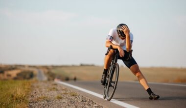 Exhausted cyclist in black helmet and sport clothing relaxing on road after long riding. Background of countryside. Concept of recreation.
