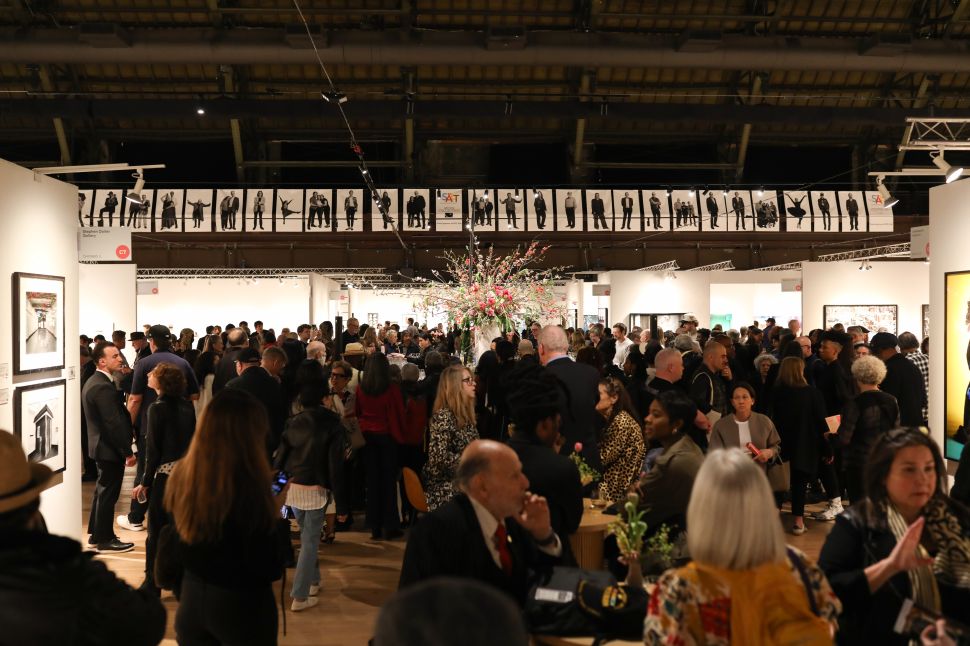A crowded VIP preview at The Photography Show at the Park Avenue Armory, with collectors and visitors gathered among gallery booths under a high industrial ceiling