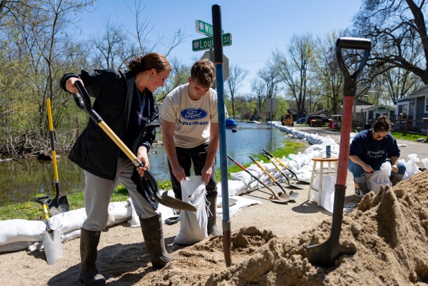 Josie Bell, left, and Ryan Heuser fill sandbags along Beach Street as the Fox River rises on April 20, 2026, in Crystal Lake. (Brian Cassella/Chicago Tribune)