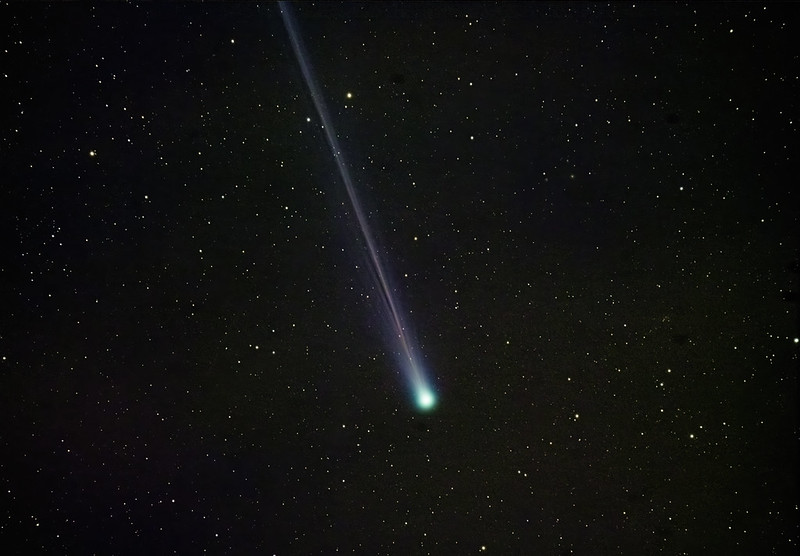 A comet with a long skinny tail against background stars.