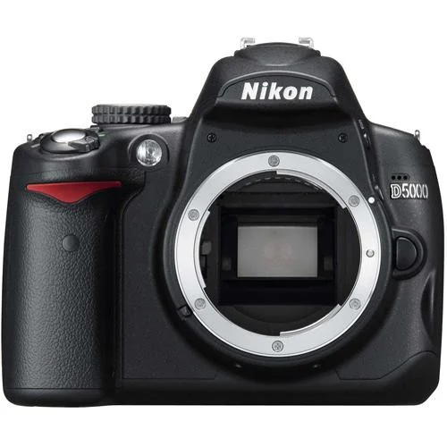 A black Nikon D5000 DSLR camera body with no lens attached, showing the lens mount and mirror inside. The brand name "Nikon" is visible above the lens mount.