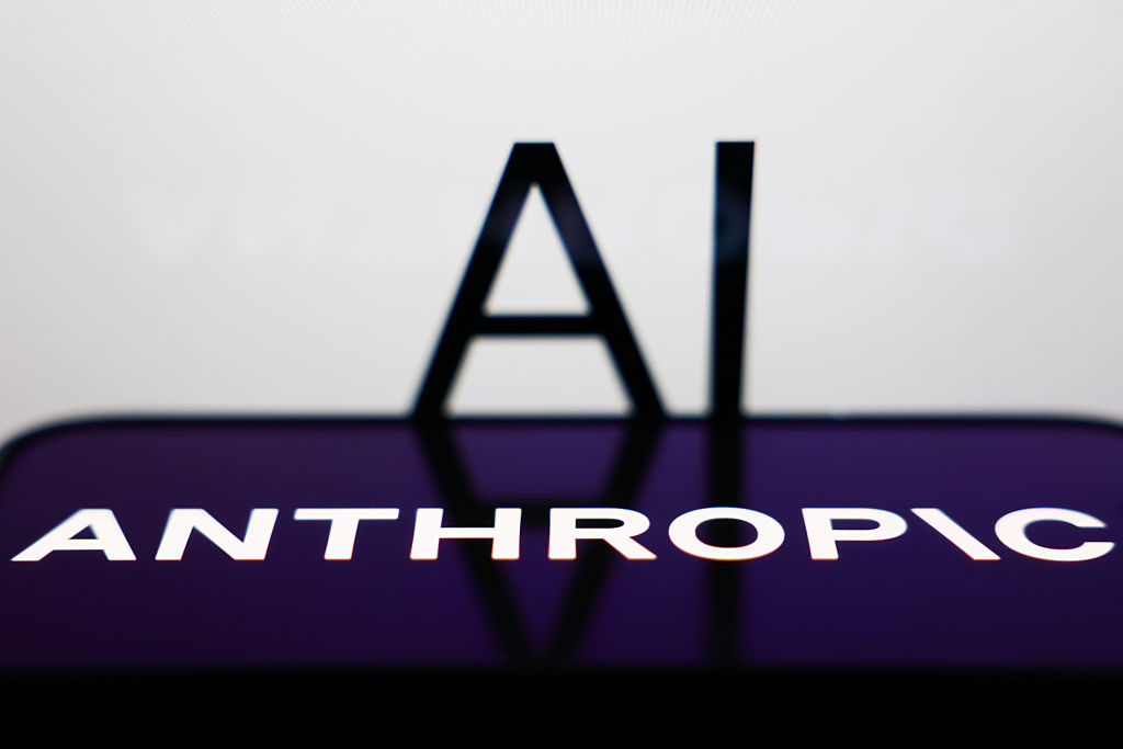 AI sign displayed on a screen and Anthropic logo displayed on a phone screen are seen in this illustration photo.