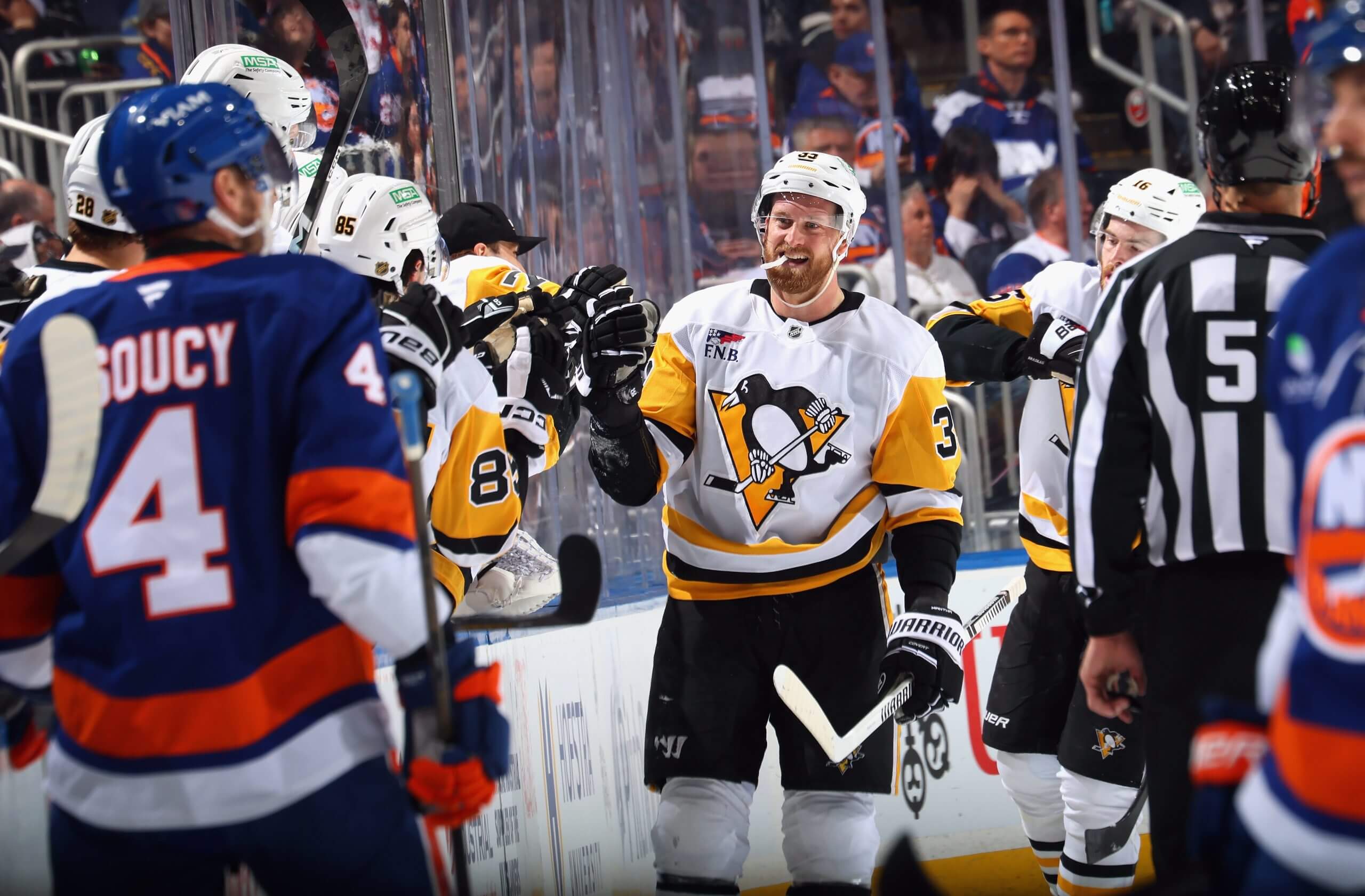 Anthony Mantha makes his way down the Penguins fist-bump line, with some Islanders players and a ref in the foreground.