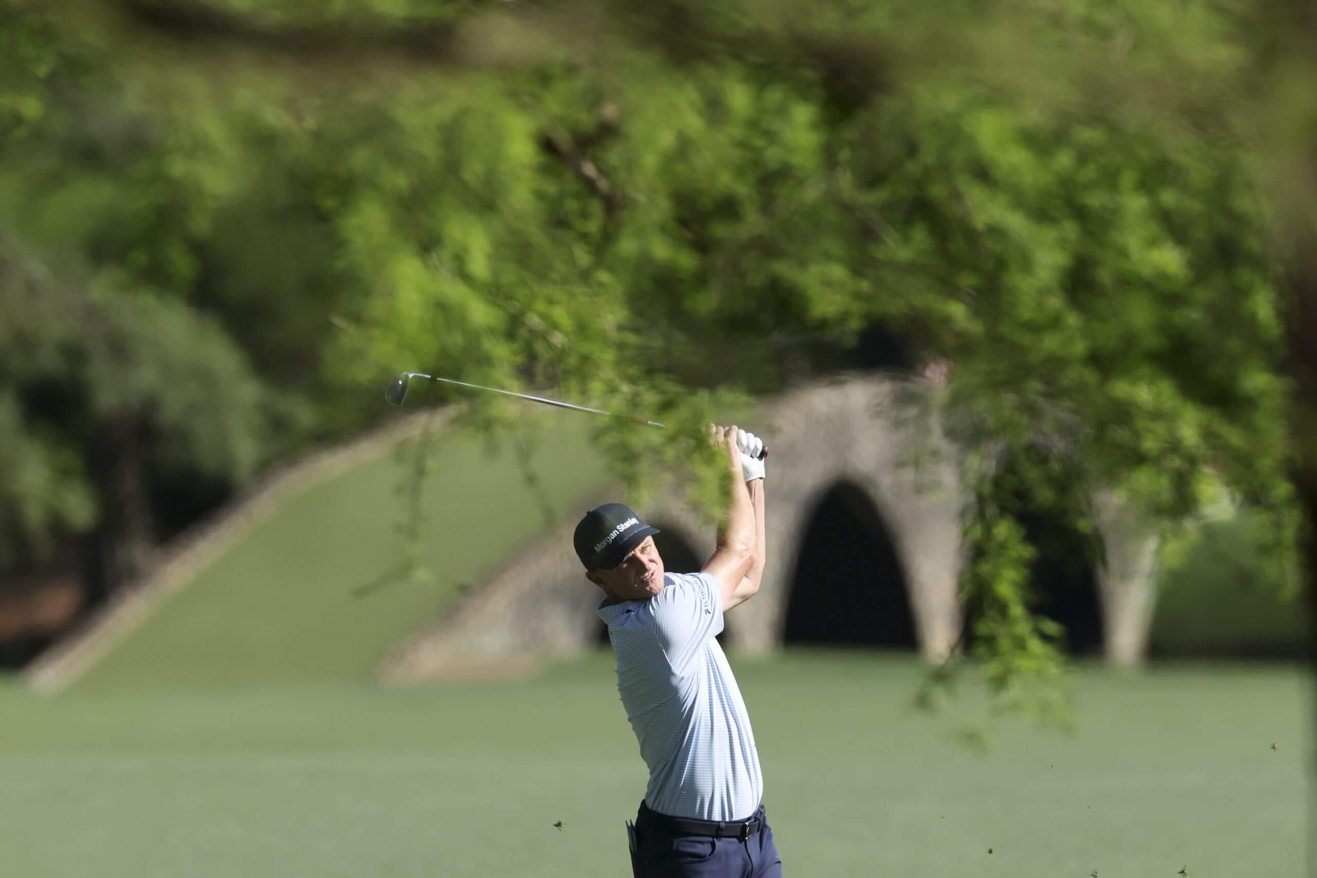 Justin Rose follows through on his swing and watches his shot on the 13th hole.