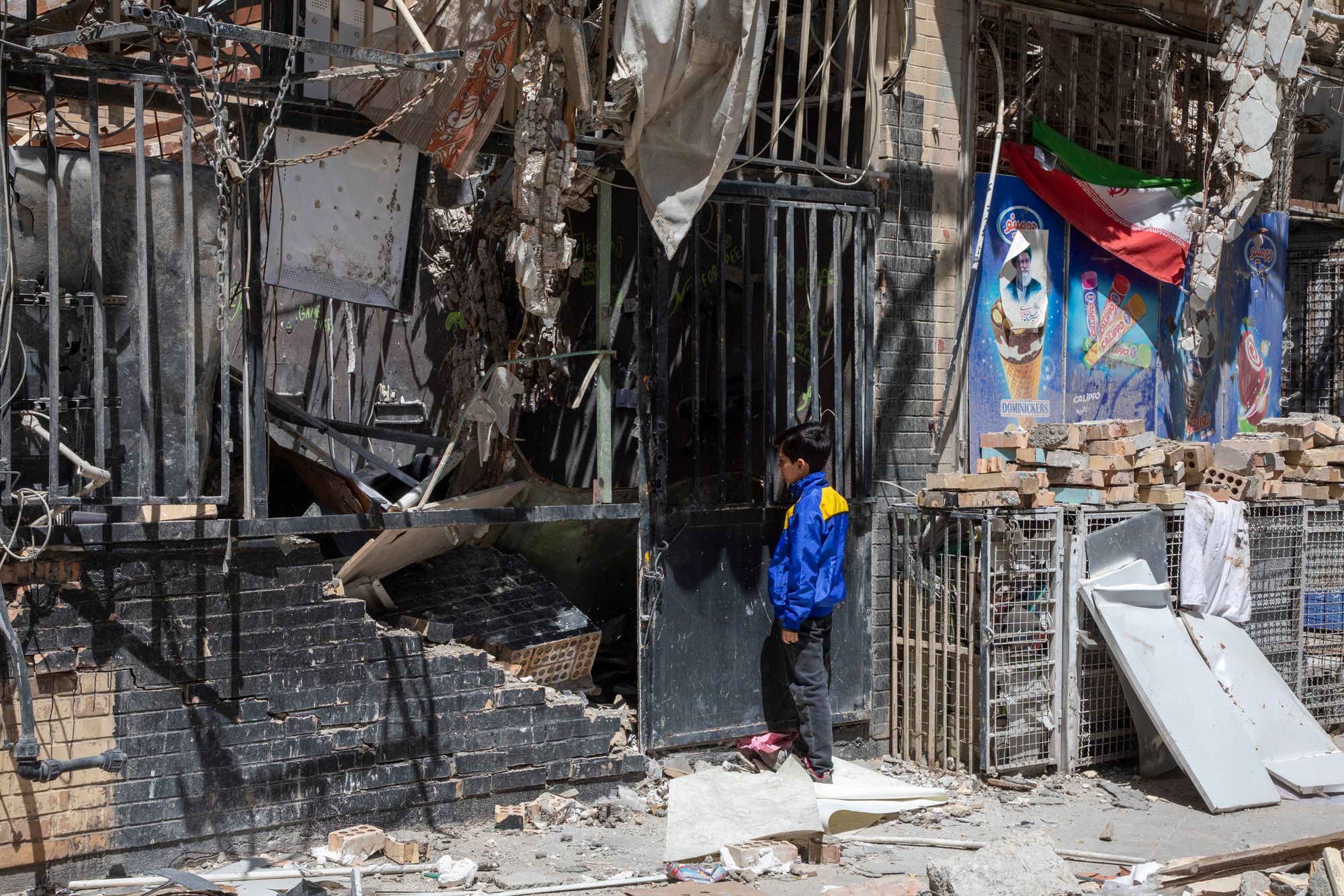 A boy peers into a damaged residential building that, according to Iranian authorities, was hit by a strike on March 4 during the U.S.-Israeli military campaign, on April 14, 2026 in Tehran, Iran.