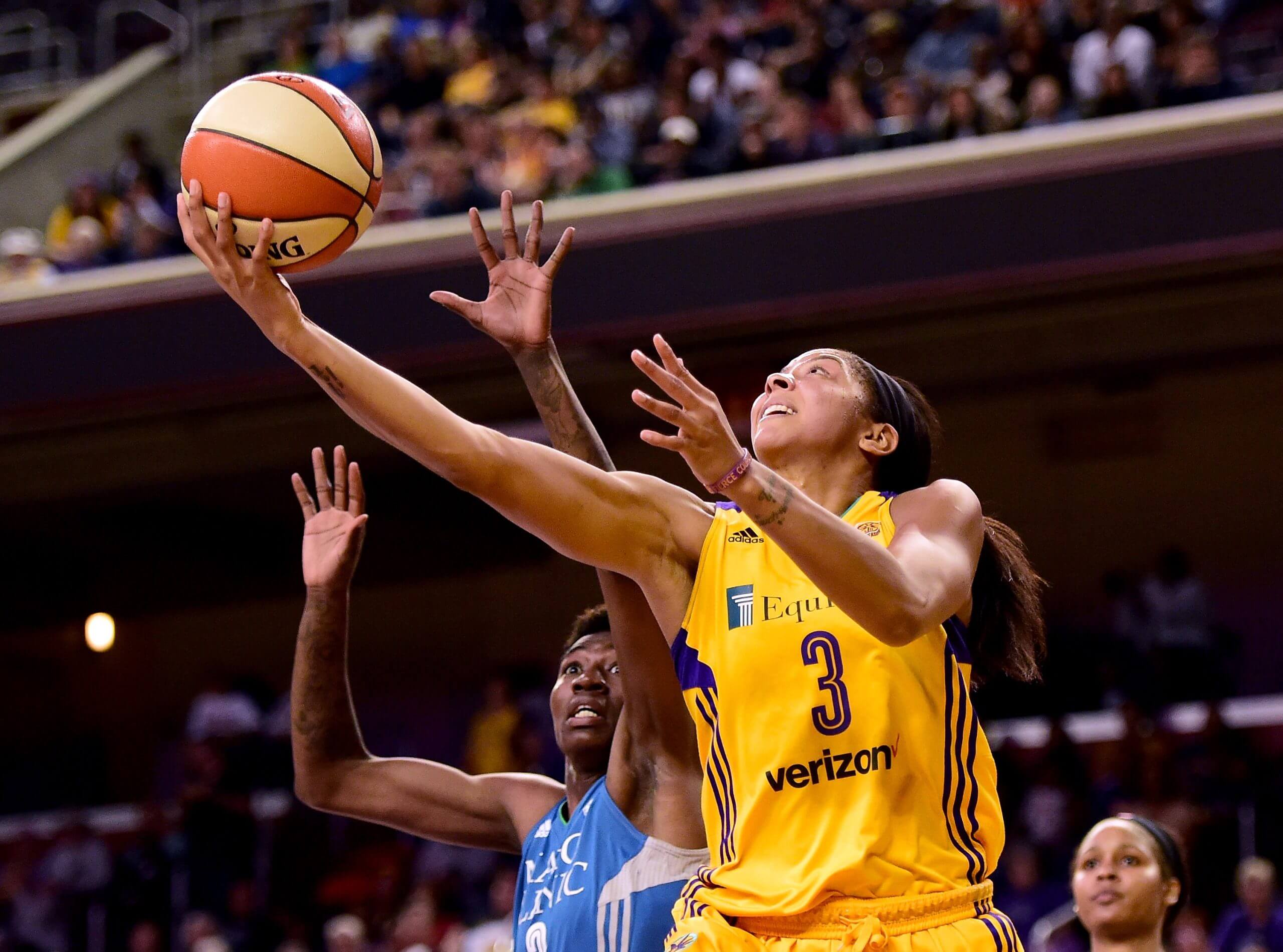 An image of WNBA player Candace Parker attempting a layup with the ball in her right hand while a defender pursues her from behind with arms raised.
