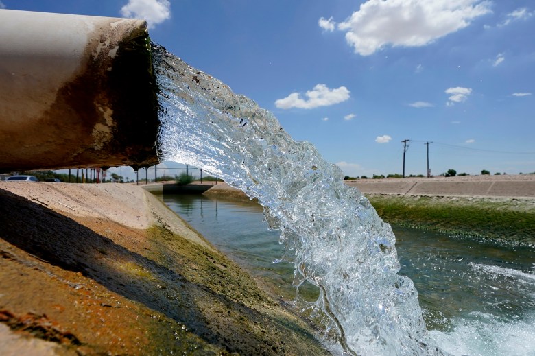 Water flows from a big pipe into an irrigation canal