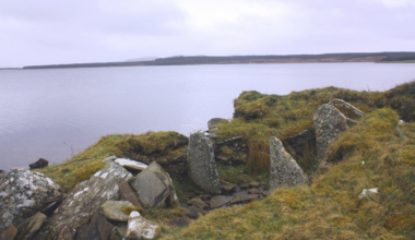 A moss-covered stone tomb on the edge of a coastline in Scotland