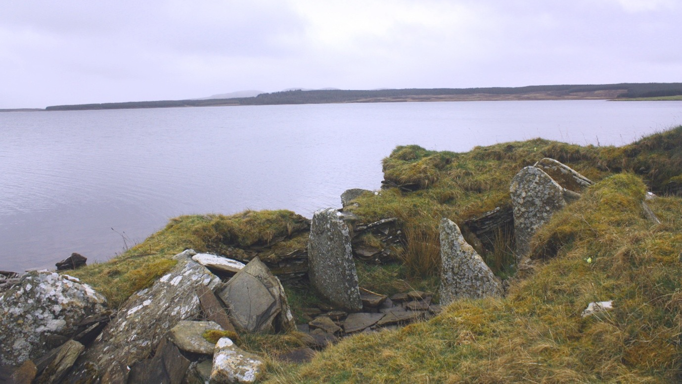 A moss-covered stone tomb on the edge of a coastline in Scotland