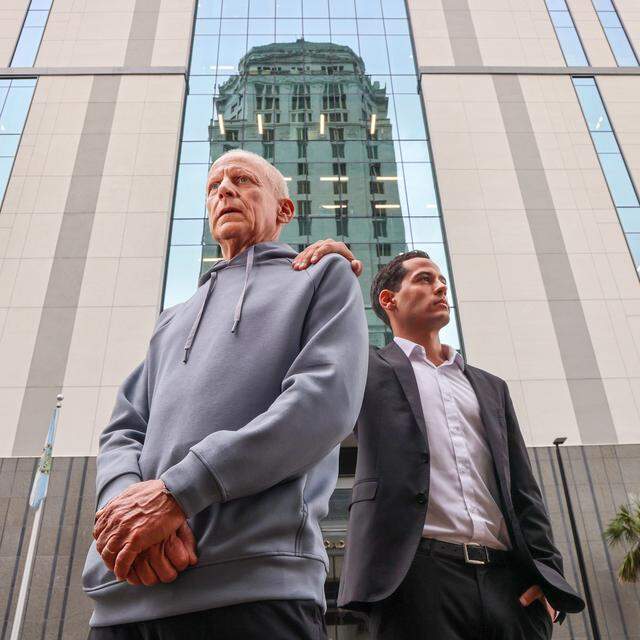 Pablo Langesfeld, left, who lost his daughter and son-in-law in the 2021 Champlain Towers collapse, stands with his son Martin, right, outside the Osvaldo N. Soto Miami-Dade Justice Center in Miami, Tuesday, April 7, 2026. Langesfeld, now battling advanced pancreatic cancer, is suing Oscar Health Insurance for denying coverage of a drug therapy his doctors recommend, underscoring broader struggles over access to treatment.