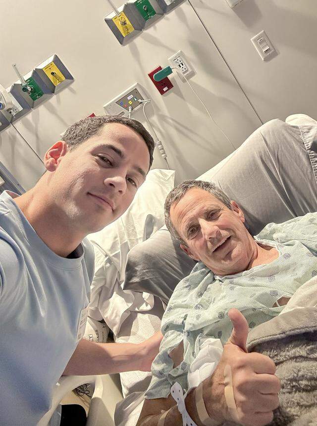 Pablo Langesfeld, right, who lost his daughter and son-in-law in the 2021 Champlain Towers collapse, gives a thumb-up with his son Martin Langesfeld, left, during a hospital visit. (Photo Courtesy of Martin Langesfeld)Langesfeld, now battling advanced pancreatic cancer, is suing Oscar Health Insurance for denying coverage of a drug therapy his doctors recommend, underscoring broader struggles over access to treatment. 
