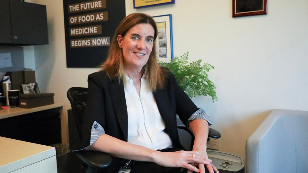 Sue Daugherty, CEO of MANNA in Philadelphia, sits in a chair smiling at the camera