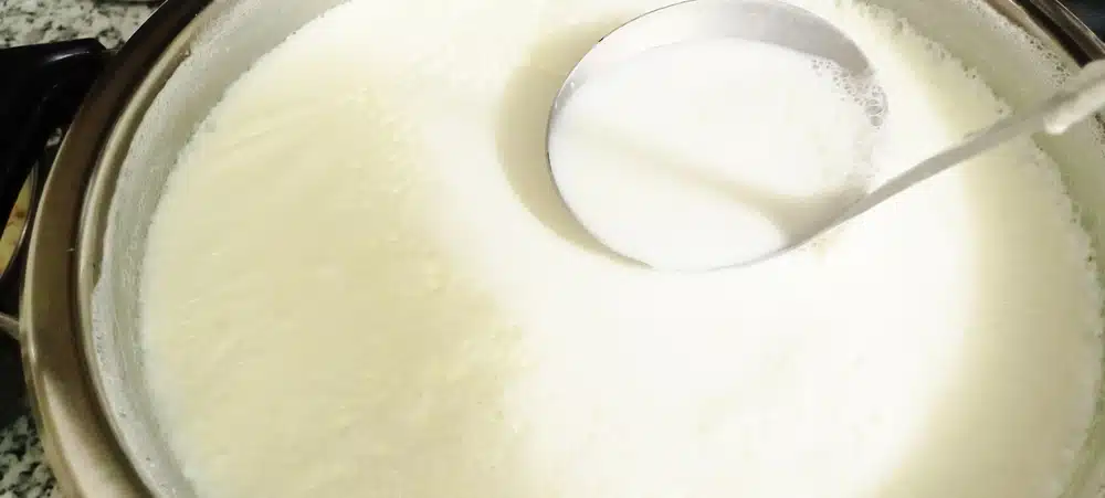 Milk,boiling,in,a,pot,with,a,metal,spoon,on