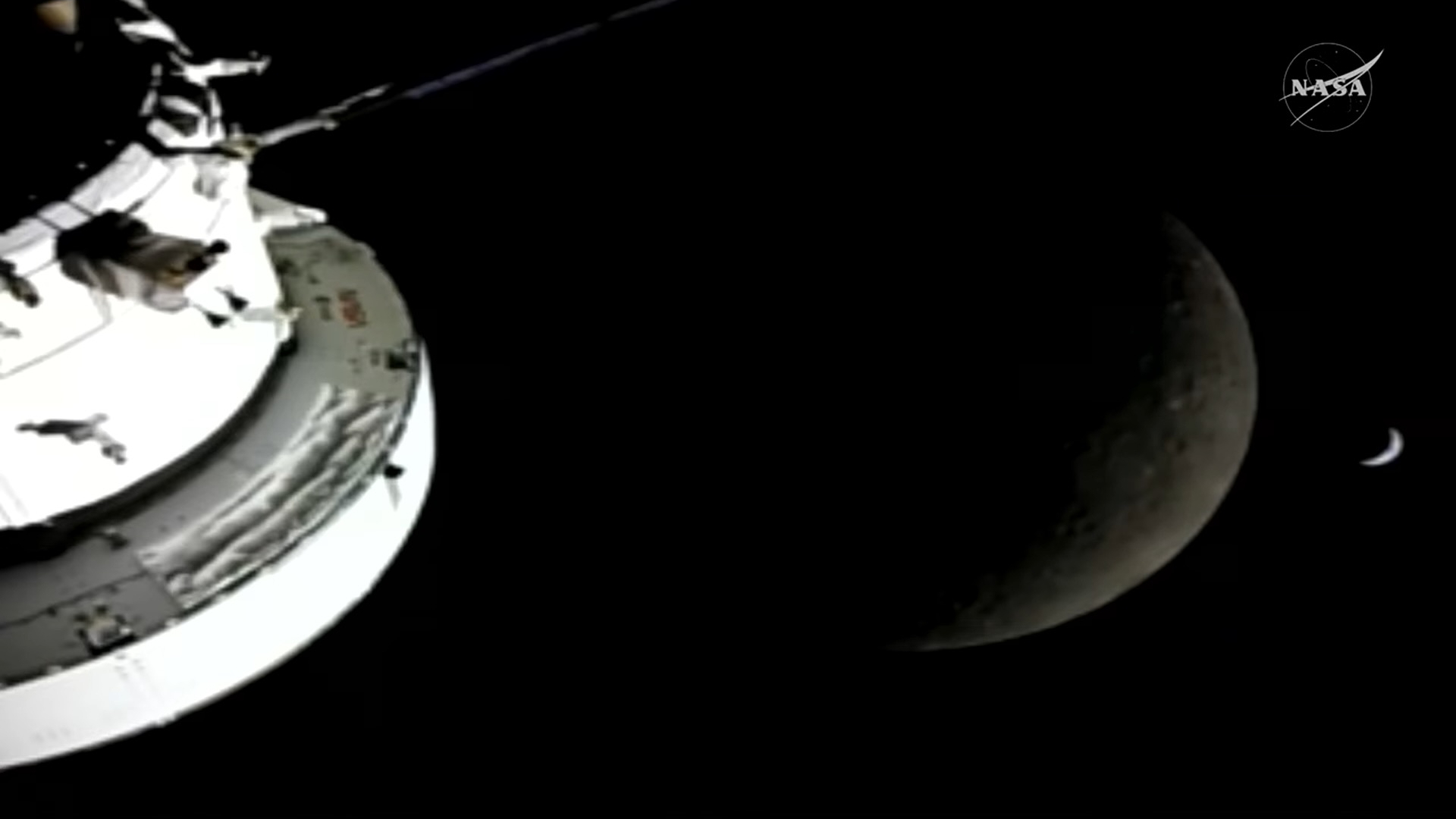 view of a spacecraft in the foreground with the moon and a crescent earth in the background