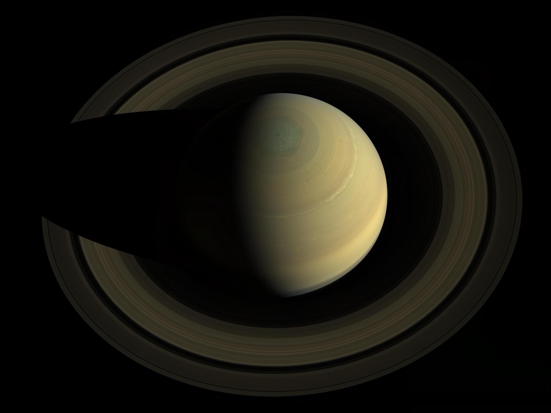 A view of Saturn and its rings with half the planet in shadow, showing the north polar region and detailed ring structure against a black background.