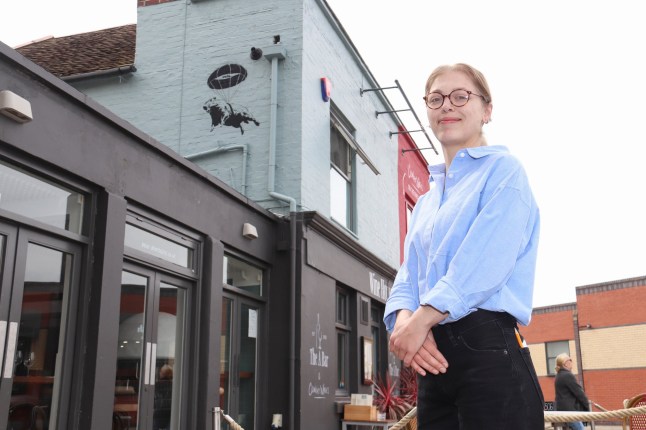 Pictured: Manager, Penelope Elliott Martin with the artwork on the A Bar wall in Old Portsmouth. Banksy-style artworks depicting a capybara have started appearing on pubs near a zoo where one of the giant rodents is on the loose. Pub managers near Marwell Zoo say they have been puzzled by capybara murals appearing overnight. Staff found the murals of the covert capybara with a parachute on its back painted on the side of two pubs in Hampshire when they started their shift. It is thought to be a bizarre homage to Samba the capybara who escaped from Marwell Zoo last month and is still on the run. The painting is thought to resemble Samba, the capybara who went missing from Marwell Zoo, Hants, last month. SEE OUR COPY FOR DETAILS. Please byline: Portsmouth News/Solent News ?? Portsmouth News/Solent News & Photo Agency UK +44 (0) 2380 458800