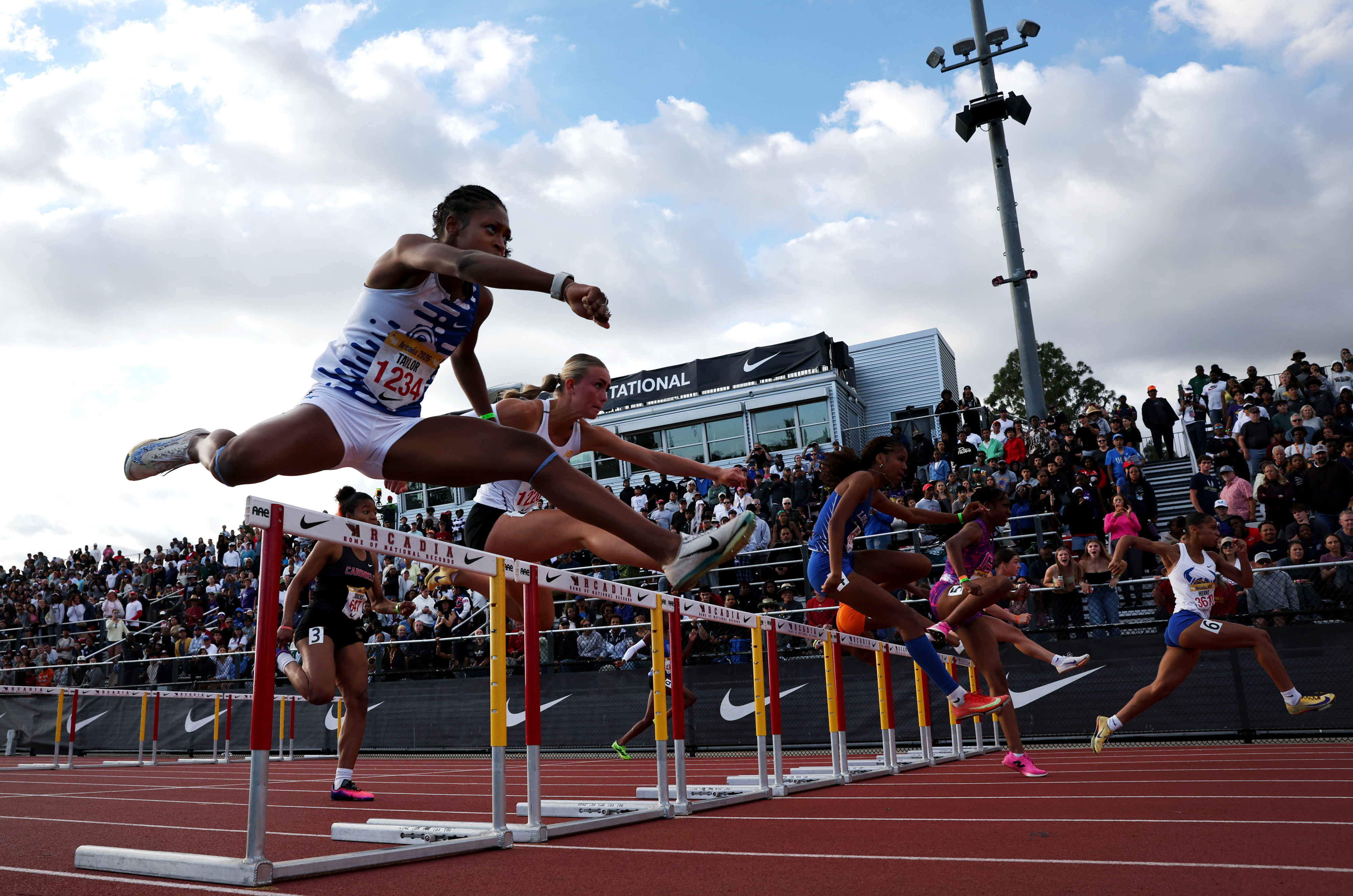 Runners compete in the girls 100 meter hurdles during the...