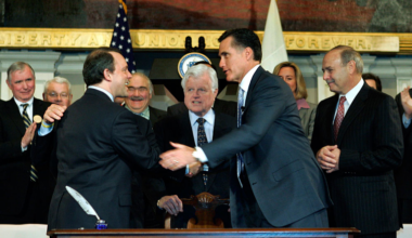 After signing Massachusetts' universal health care coverage law on April 12, 2006, then-Gov. Mitt Romney shakes hands with state Health and Human Services Secretary Timothy Murphy as Sen. Edward Kennedy and others look on at Faneuil Hall in Boston. (AP)