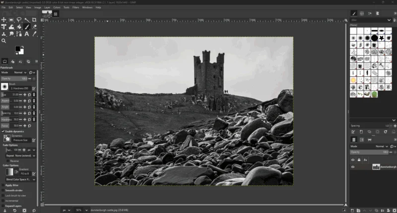 A black and white photo of a rocky landscape with an old, ruined stone tower on a hill, shown open for editing in GIMP software, with toolbars and panels visible around the image.