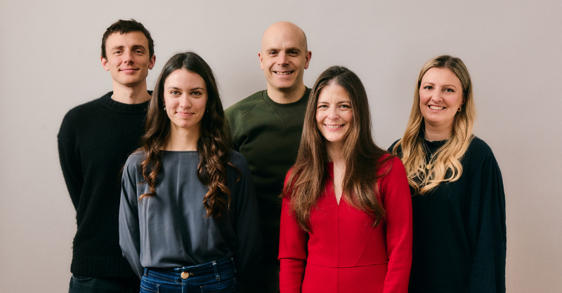 Five people stand together smiling at the camera