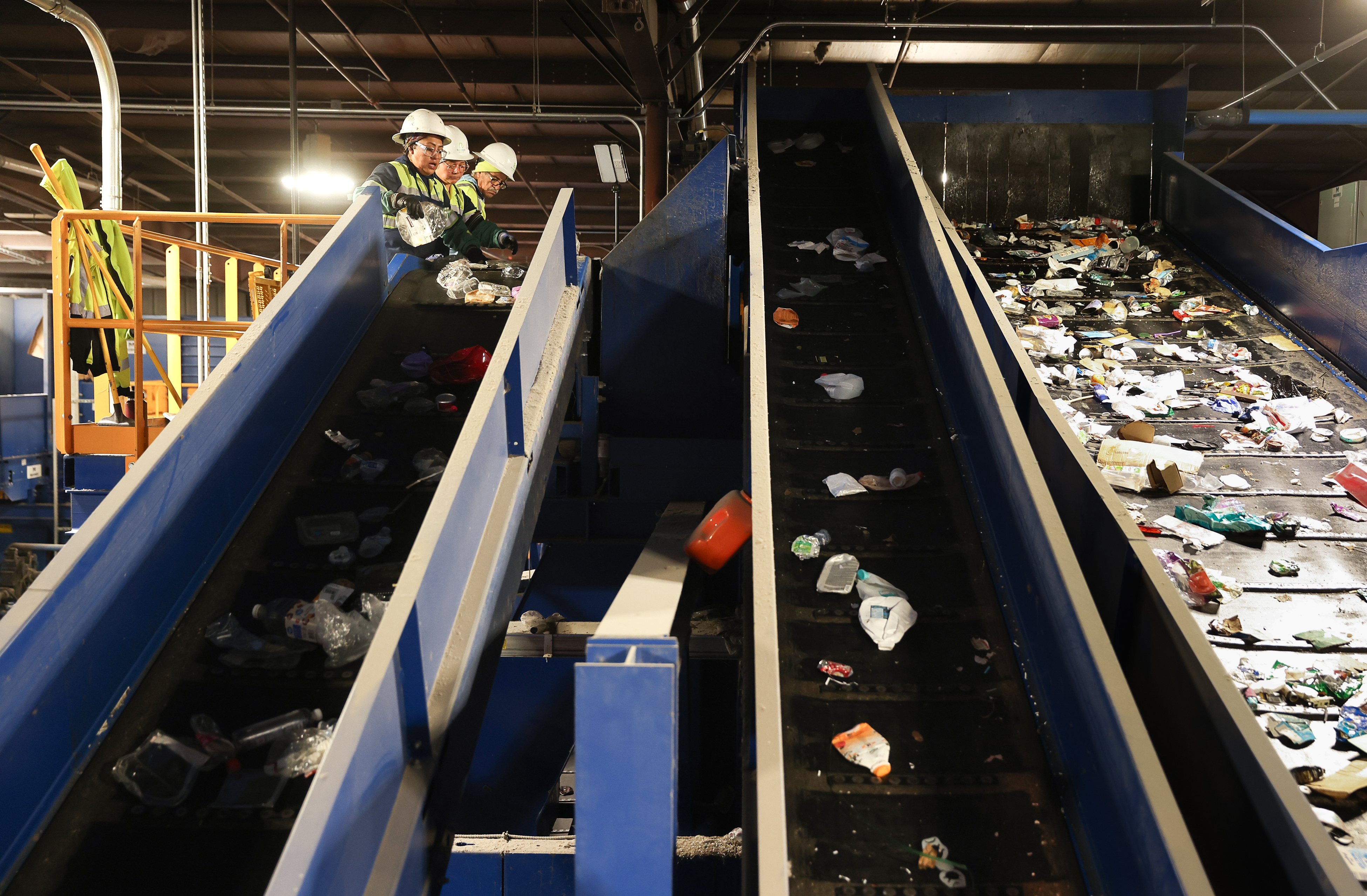 Workers remove contaminants from the plastic materials line at the...