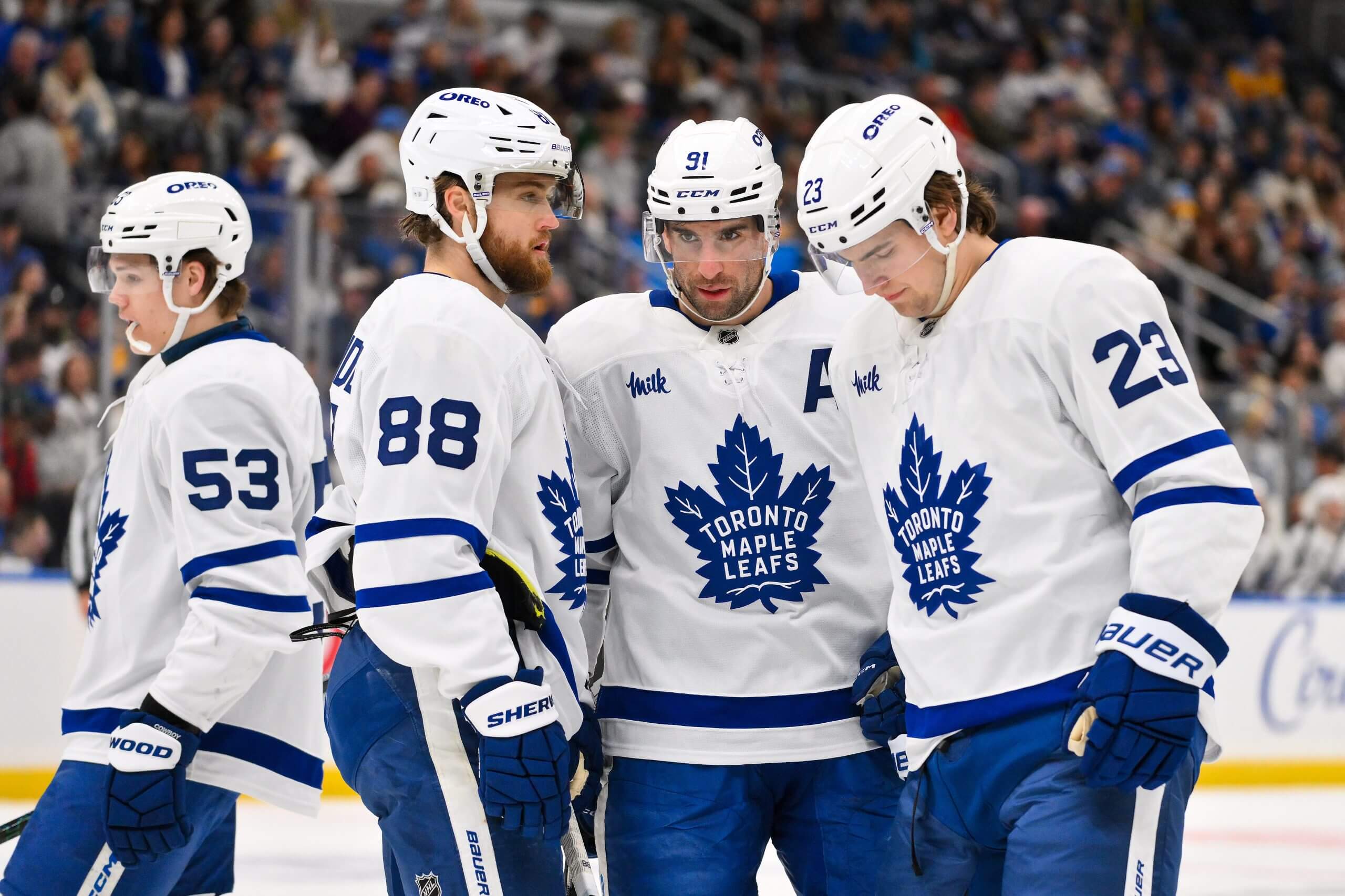 William Nylander, John Tavares and Matthew Knies confer, with another Leafs teammate in the background.