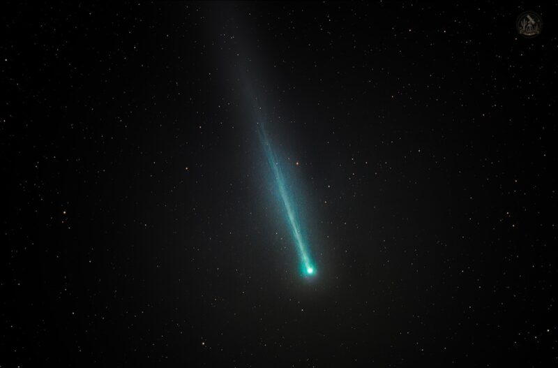 A greenish comet with a slightly fuzzy tail against background stars.