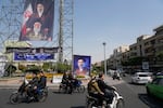 People drive their motorbikes past billboards showing the Iran's Supreme Leader Ayatollah Mojtaba Khamenei, top and right, and his father, the slain Supreme Leader Ayatollah Ali Khamenei, who was killed in U.S. and Israeli strikes on Feb. 28, in downtown Tehran, Iran, Thursday, April 16, 2026.