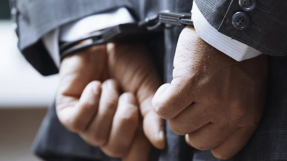 Hands of arrested businessman wearing handcuffs