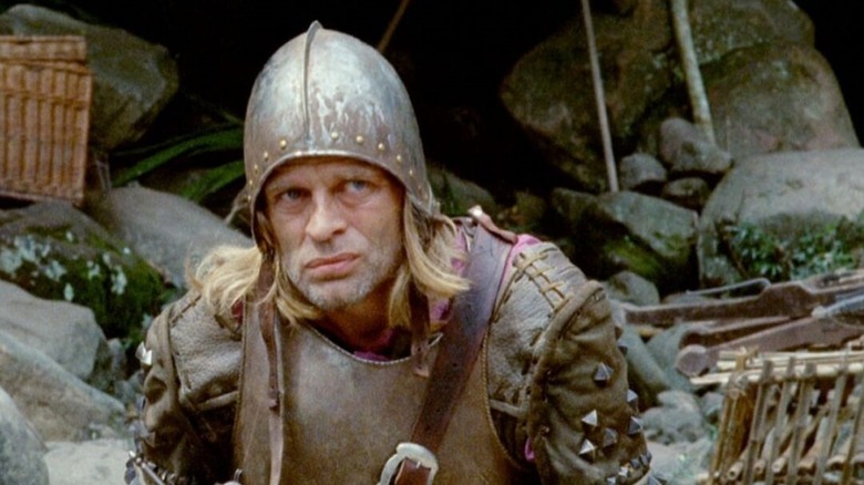 Klaus Kinski as Lope de Aguirre in Aguirre, The Wrath of God, sitting in his armor and looking up at something with discontent.
