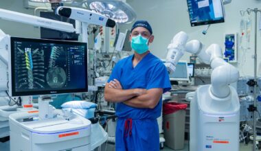 Osorio in surgical scrubs and mask, standing with arms crossed in surgical suite.
