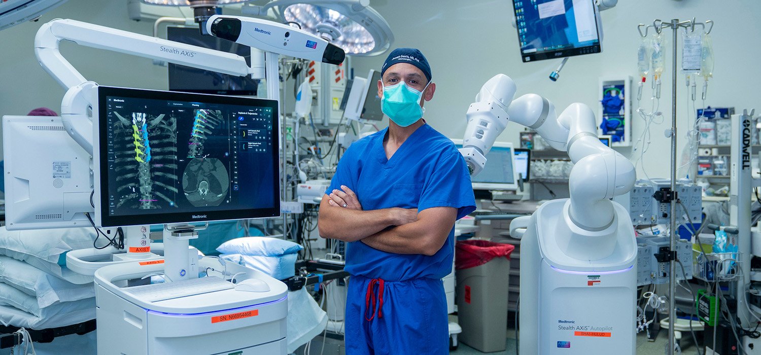 Osorio in surgical scrubs and mask, standing with arms crossed in surgical suite.