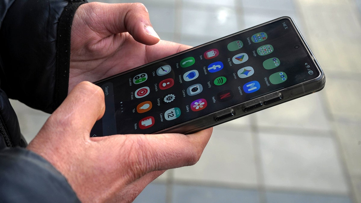 A person holding an Android smartphone in their hand.